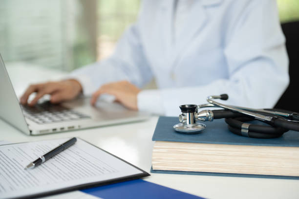 Doctor studying medical research with books and a laptop